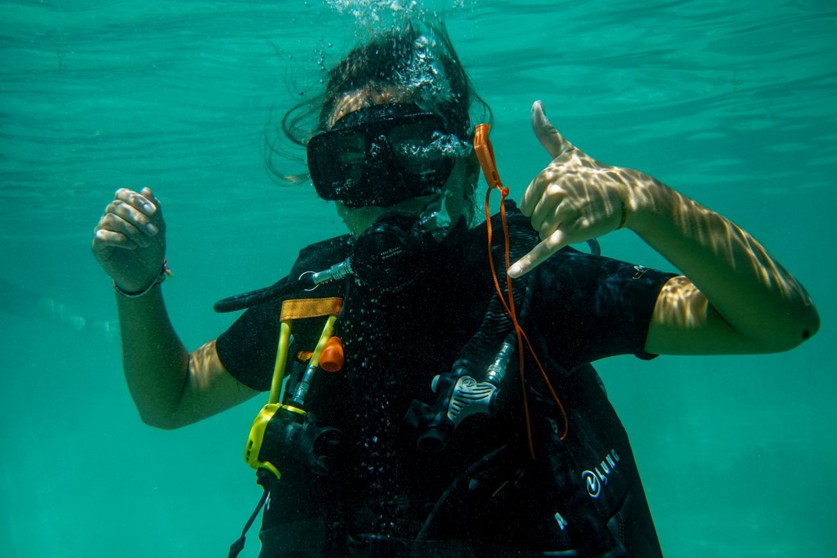 Buceador bajo el agua haciendo una señal con la mano en Port Barton